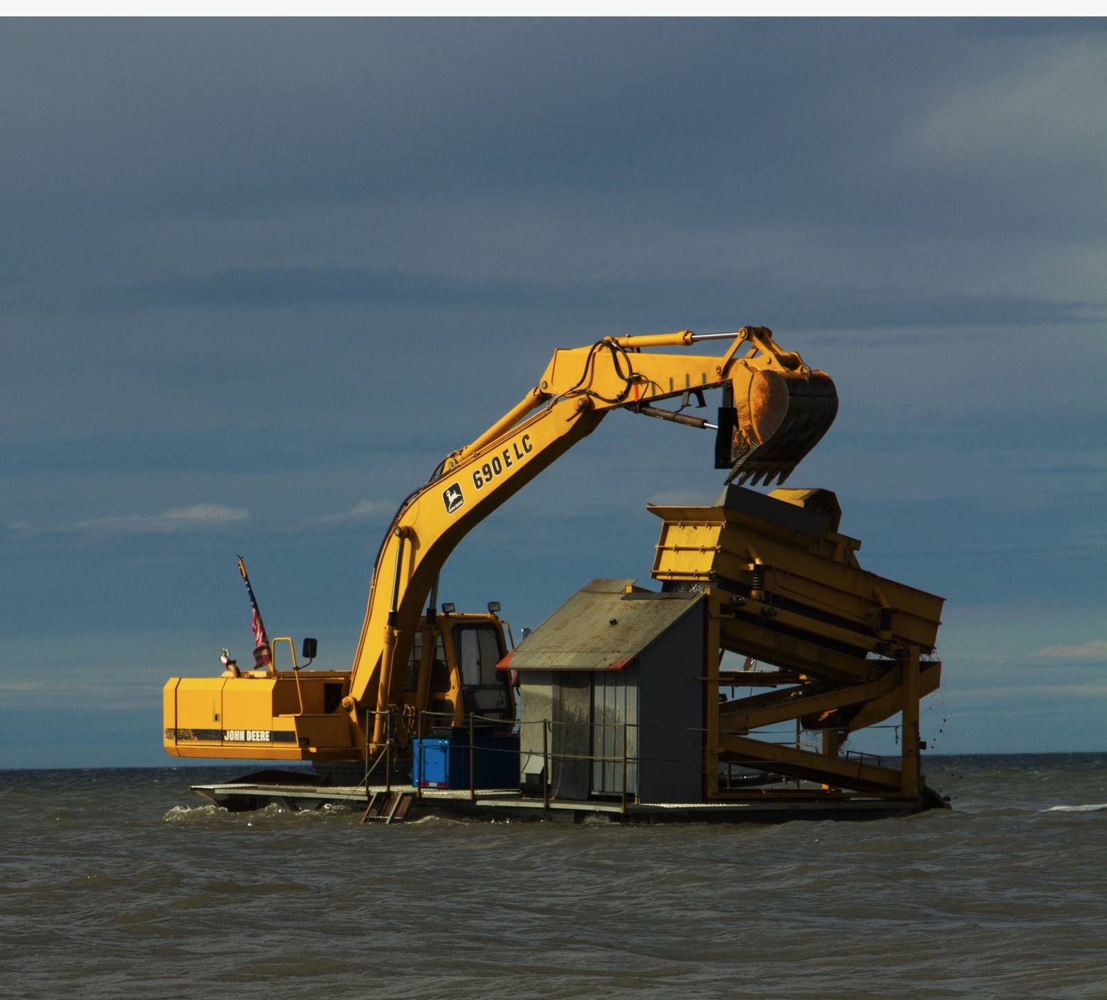 Barge-mounted M100 gold wash plant being fed by a John Deere 690E LC excavator while working offshore