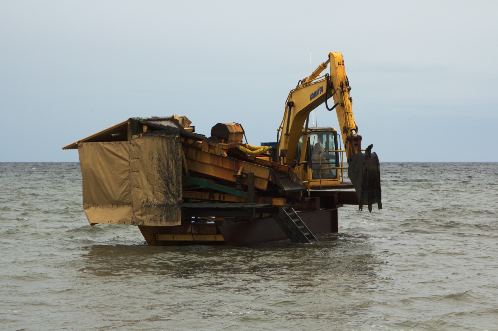 M100 gold wash plant running on a barge offshore, excavator alongside, open water in every direction
